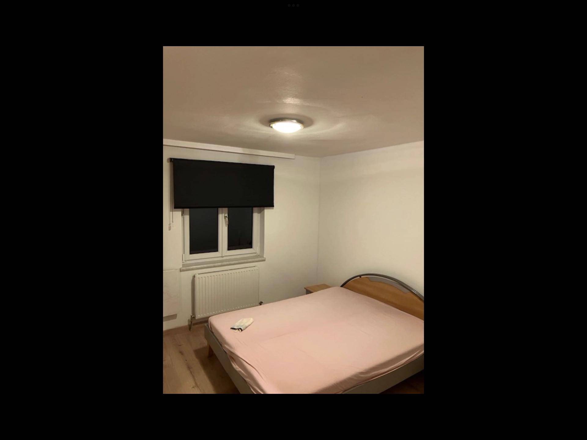 Schlafzimmer mit Holzboden, großem Kleiderschrank und einfacher Möblierung.