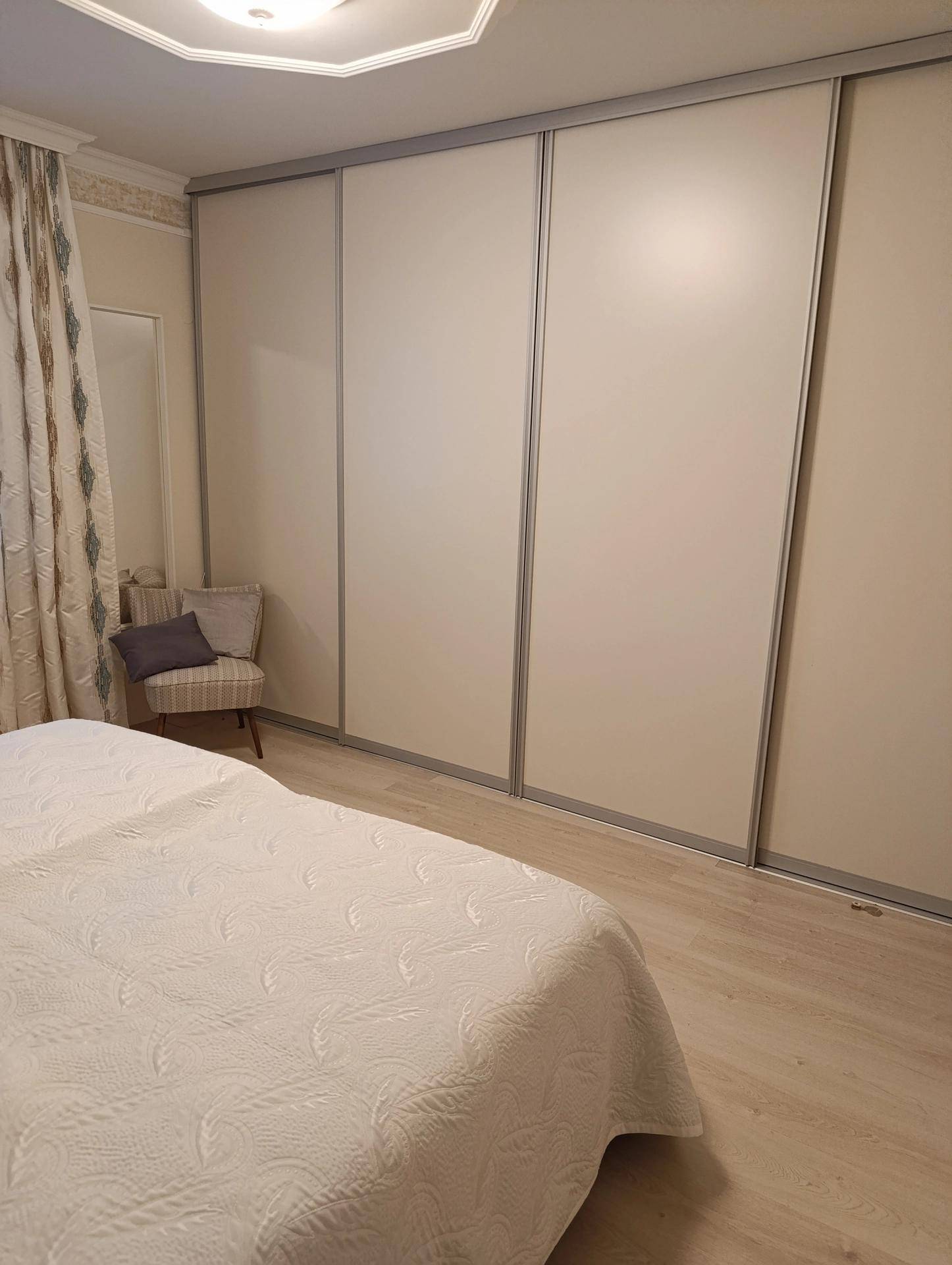 Schlafzimmer mit hellem Laminatboden, Einbauschränken und einem bequemen Bett.