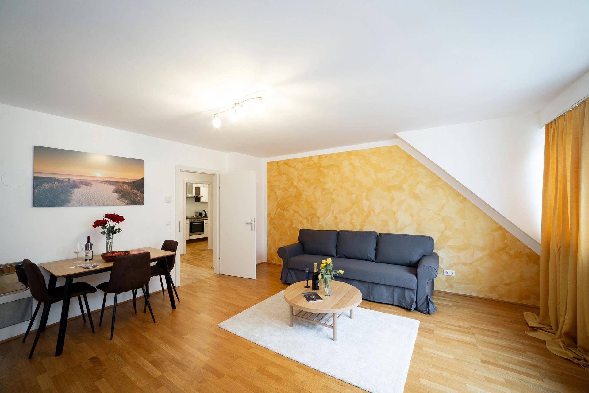 Geräumiger Wohn- und Essbereich mit Sofa, Esstisch und Zugang zur Küche.