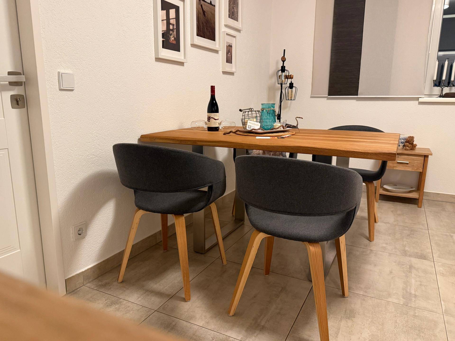 Essbereich mit modernem Holztisch und bequemen Stühlen, dekoriert mit Wandbildern.