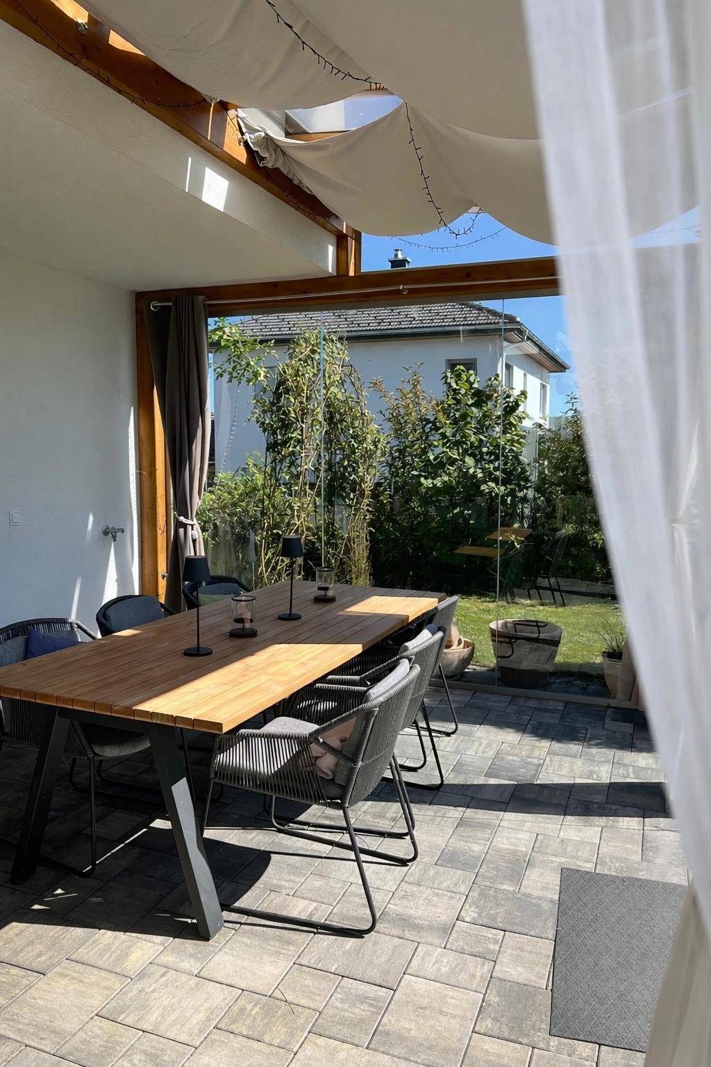 Heller Wintergarten mit großem Esstisch, bequemen Stühlen und Blick in den Garten.