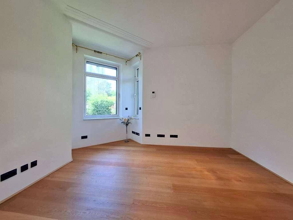 Helles Zimmer mit Parkettboden und großen Fenstern, bereit zur individuellen Gestaltung.