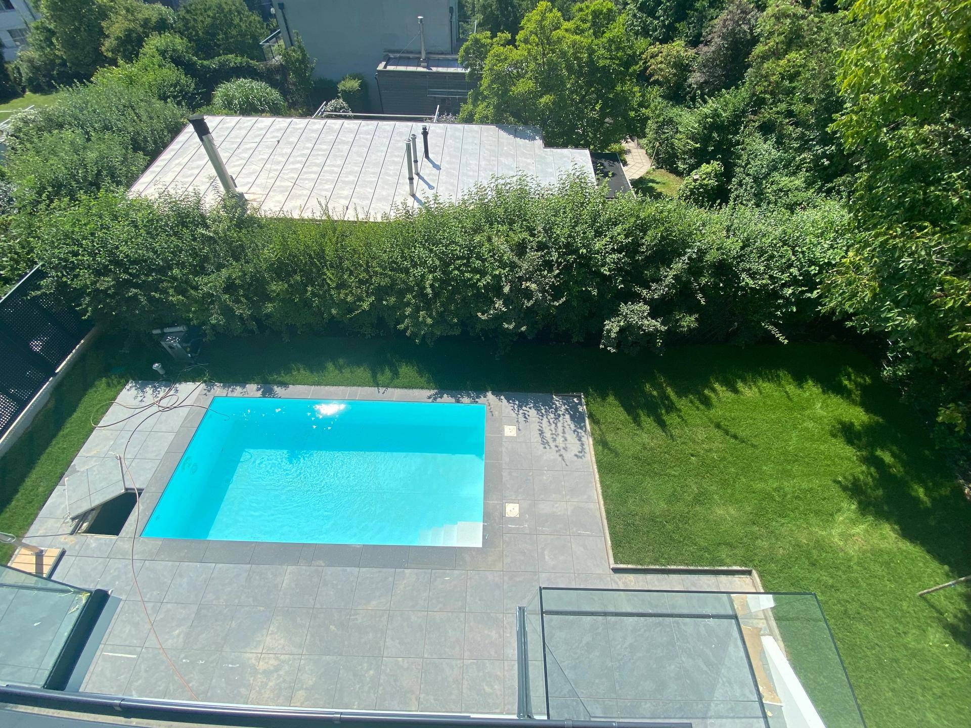 Blick von oben auf den Gartenbereich mit Pool und gepflegtem Rasen.
