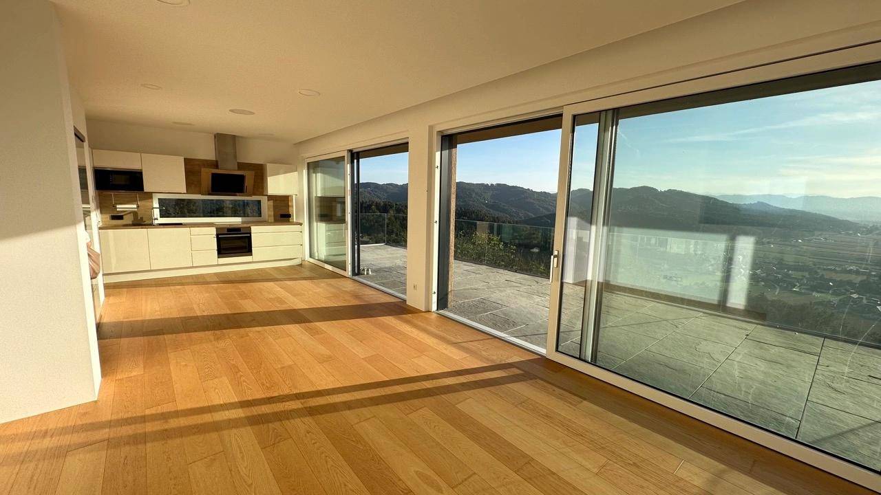 Offener Wohn- und Essbereich mit moderner Küche und großen Fenstern, die einen Panoramablick bieten.