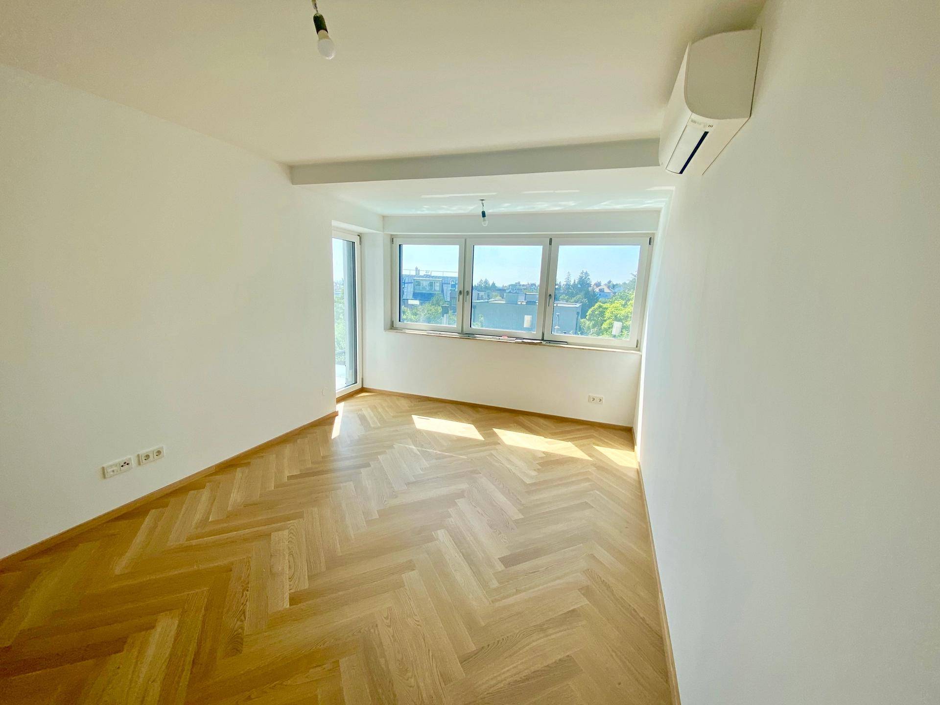 Sonniges Zimmer mit Fischgrätparkett, Klimaanlage und weitem Ausblick.