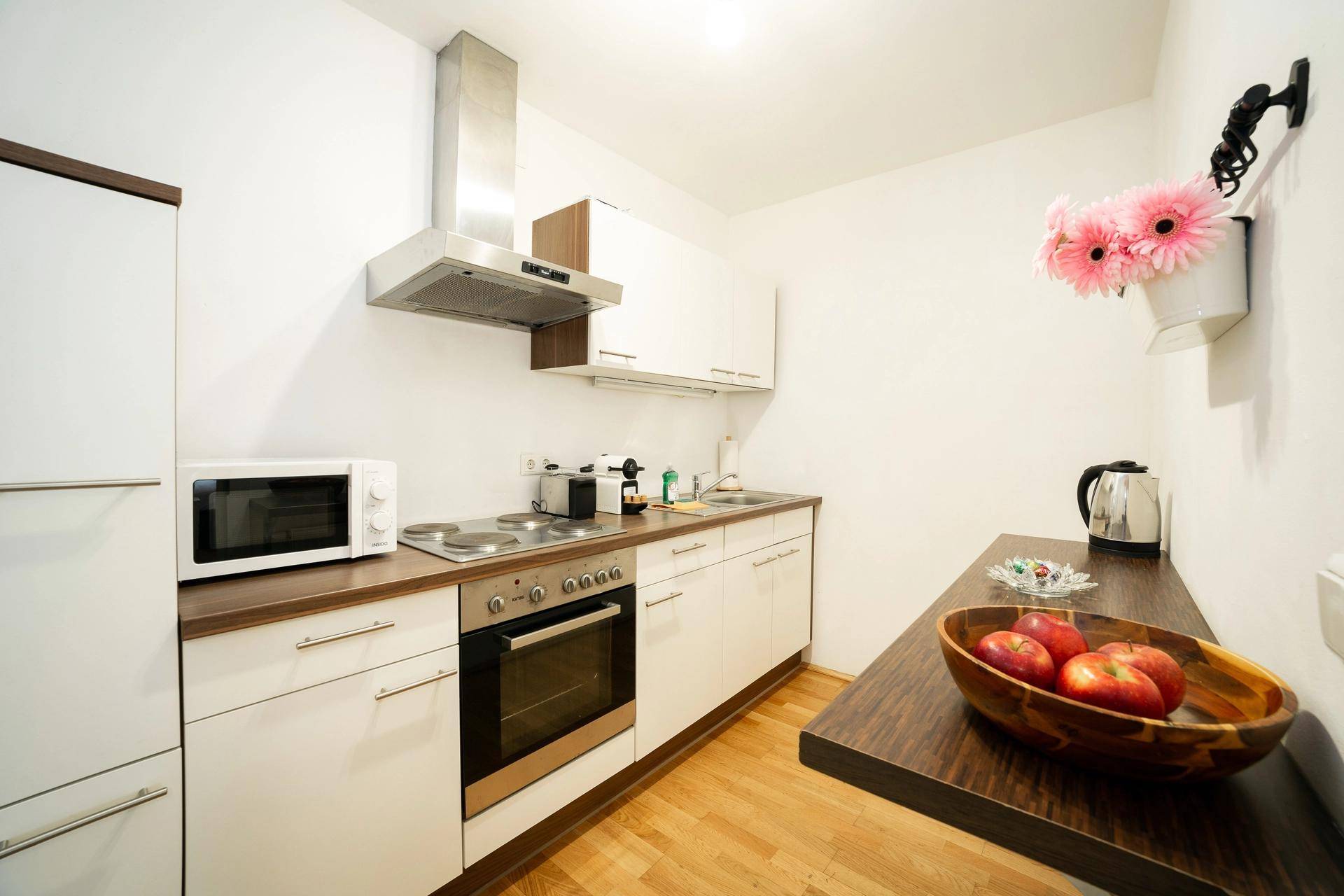 Funktionale Küchenzeile mit weißen Schränken, Holzarbeitsplatte und integrierten Geräten.