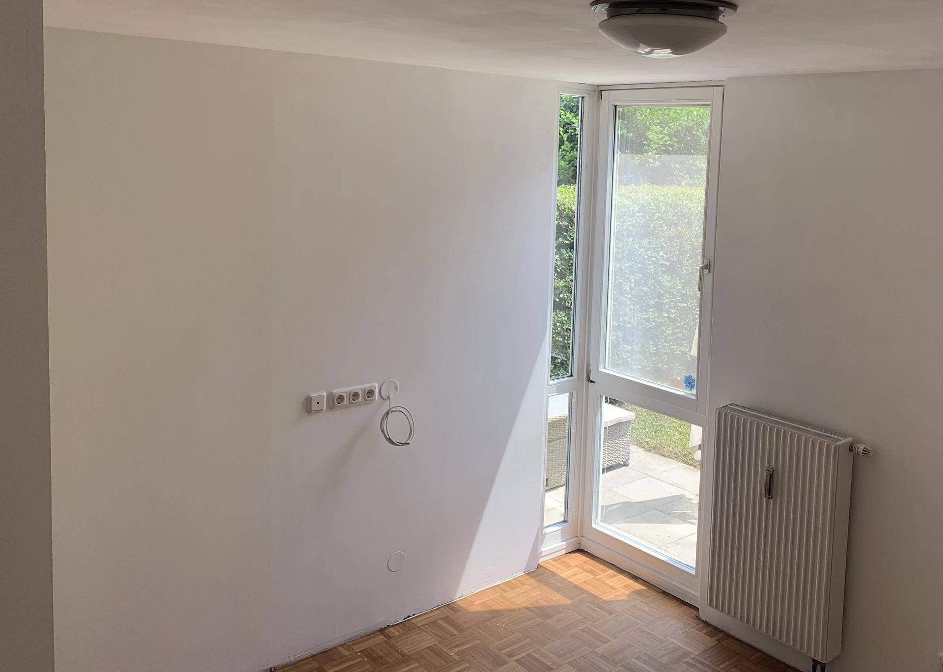 Helles Zimmer mit großer Fenstertür, die viel Licht spendet und Zugang zum Außenbereich ermöglicht.