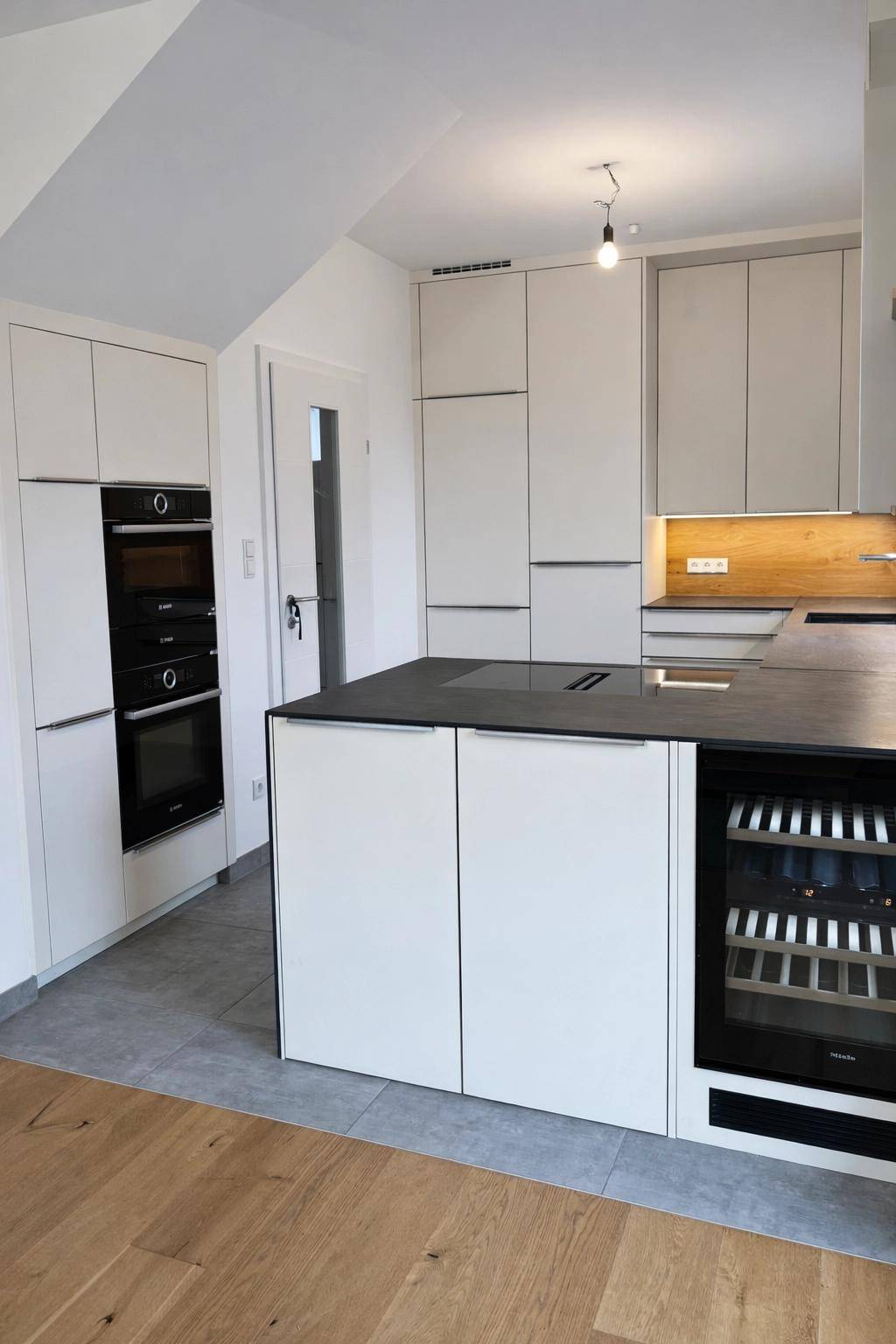 Helle Küche mit integrierten Backöfen, Kücheninsel und modernem Design.