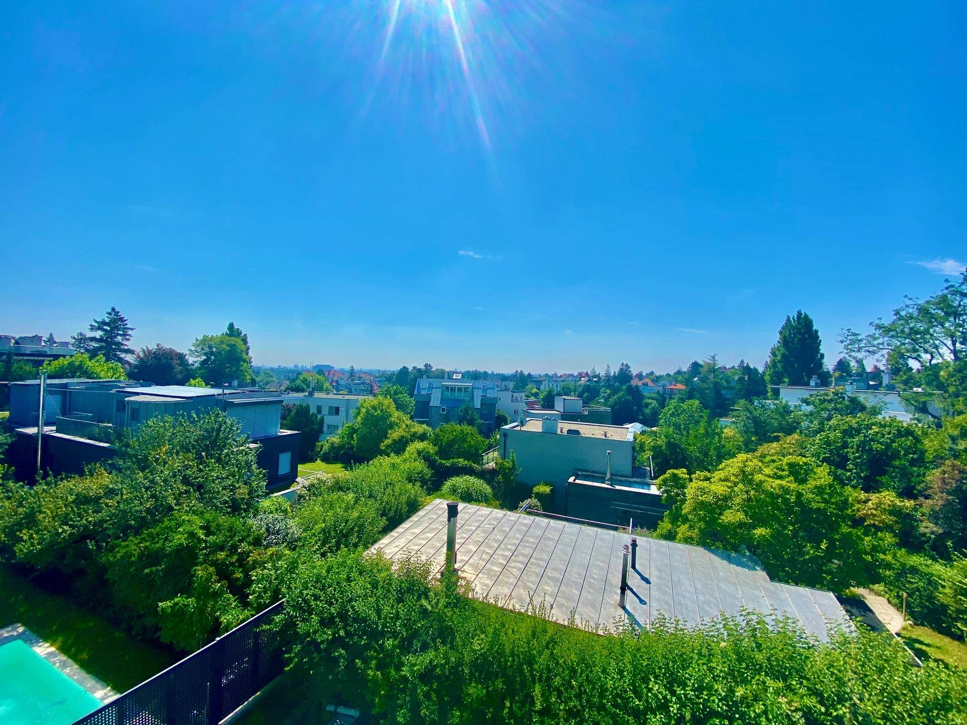 Weitläufiger Blick über die Stadt und grüne Umgebung an einem sonnigen Tag.