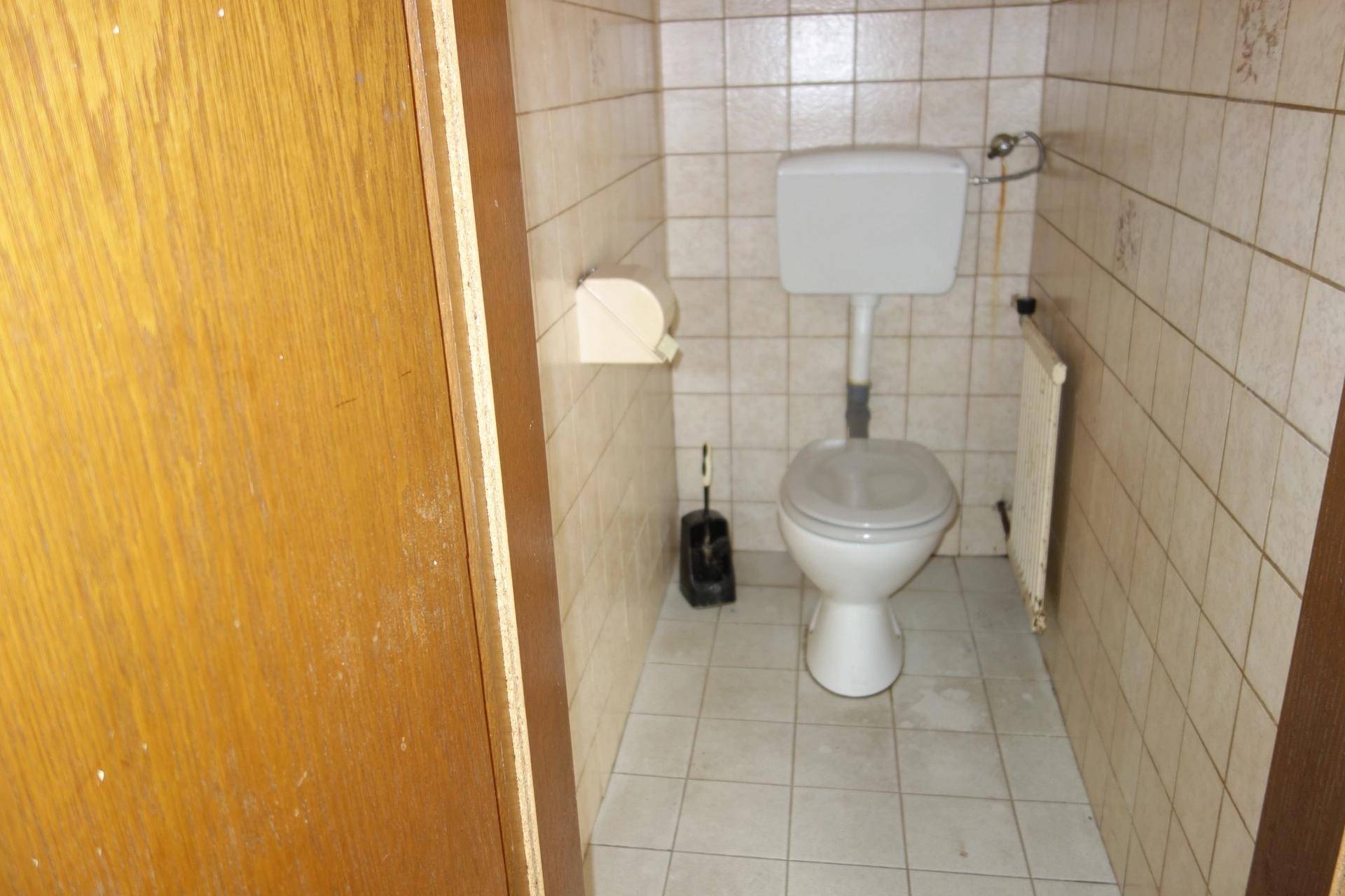 Kleines WC mit hell gefliesten Wänden und Boden sowie einer Toilette.