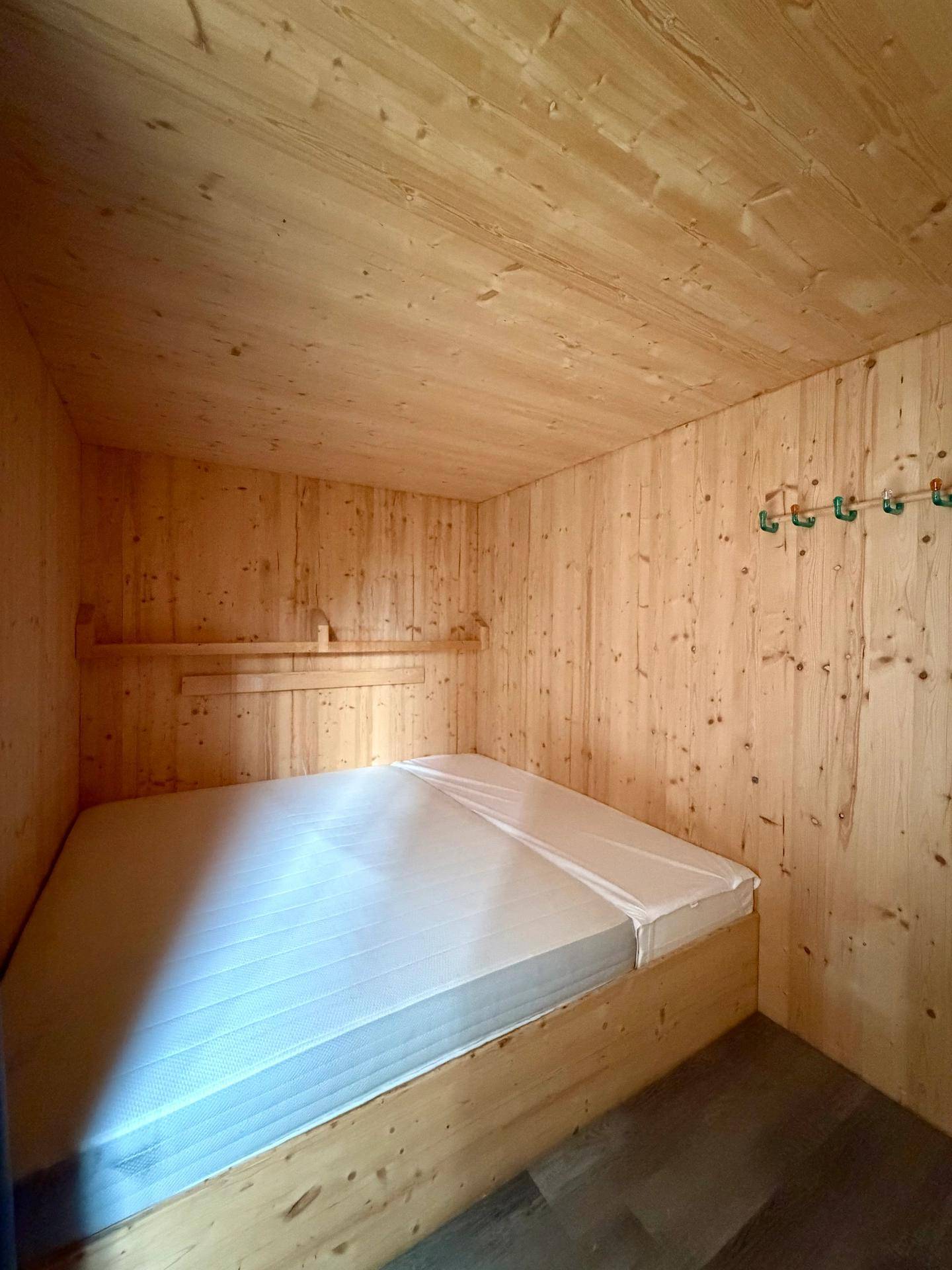 Gemütliches Schlafzimmer mit Holzwänden und -decke, ideal als Gästezimmer.