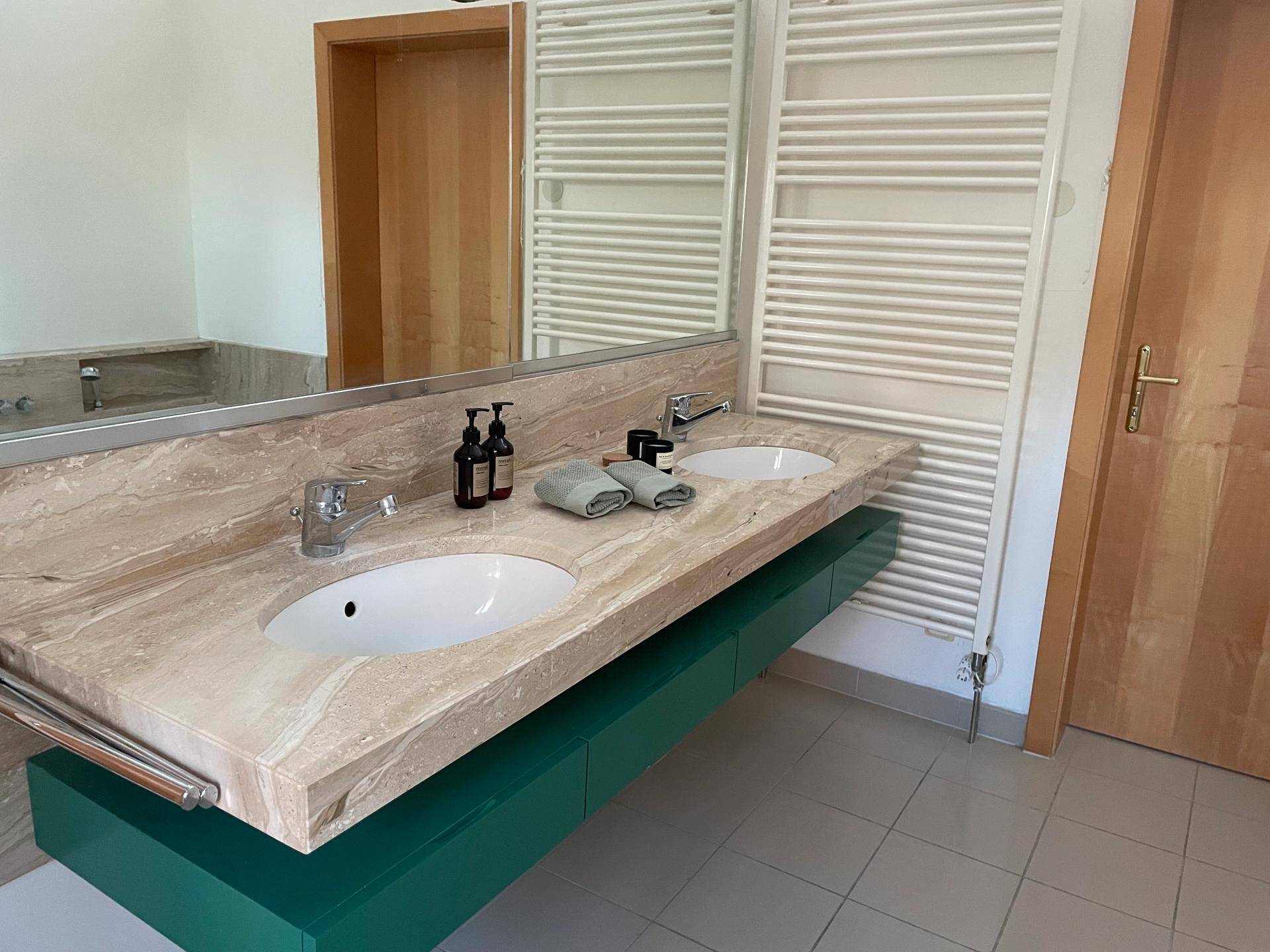 Modernes Badezimmer mit Doppelwaschbecken, Marmorplatte und beheiztem Handtuchhalter.