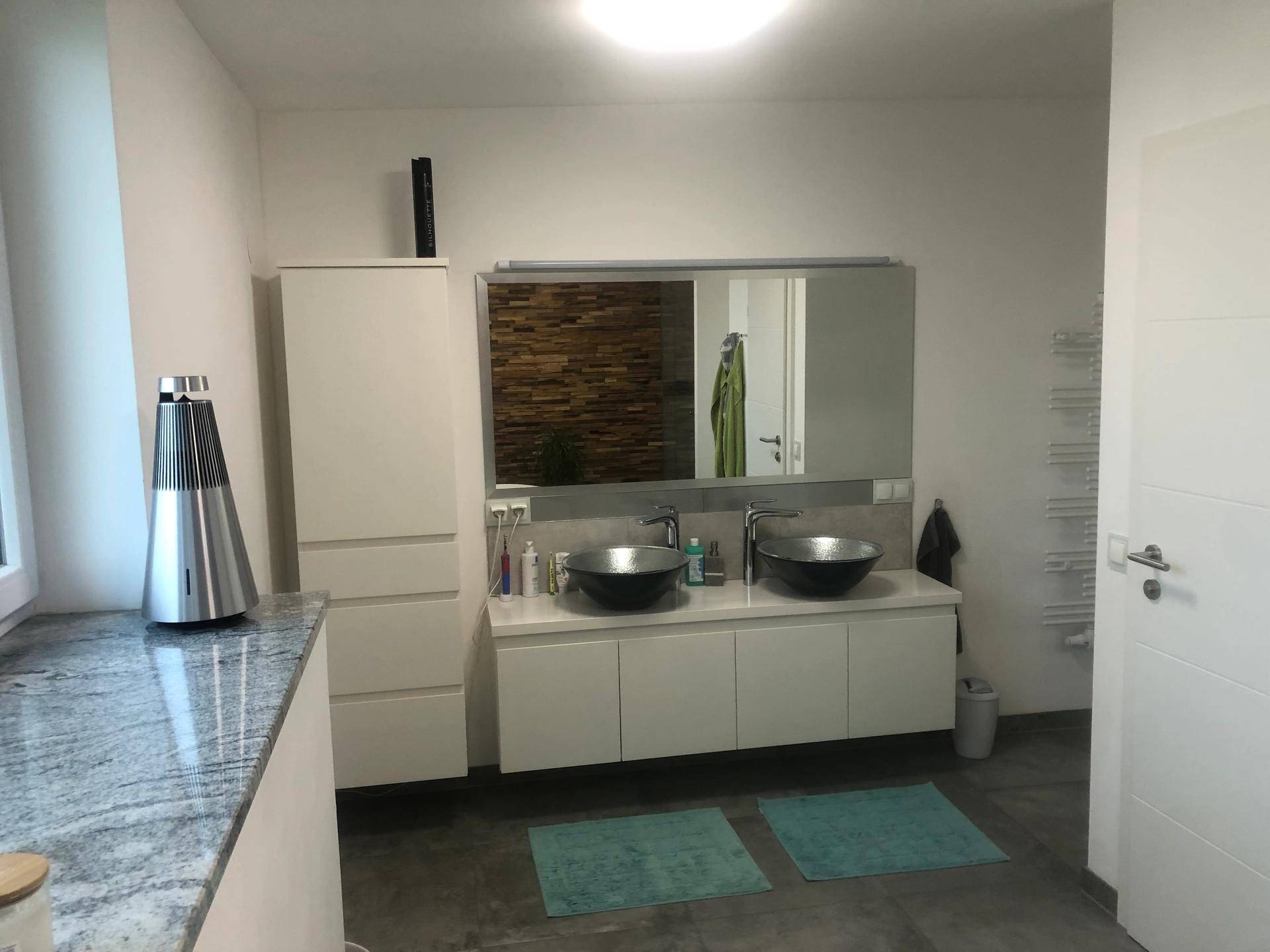 Elegantes Badezimmer mit Doppelwaschbecken, großem Spiegel und moderner Einrichtung.