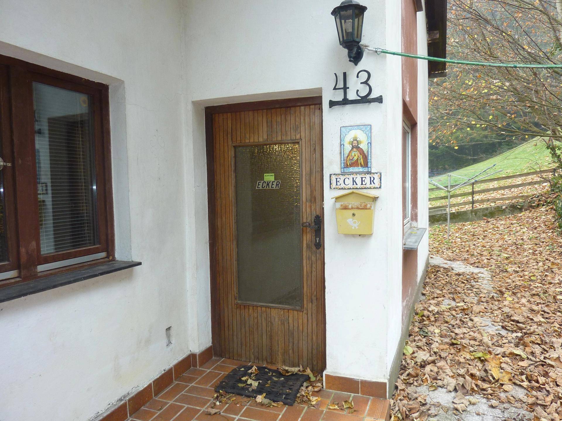 Eingangsbereich des Hauses mit Holztür, Hausnummer und Briefkasten.