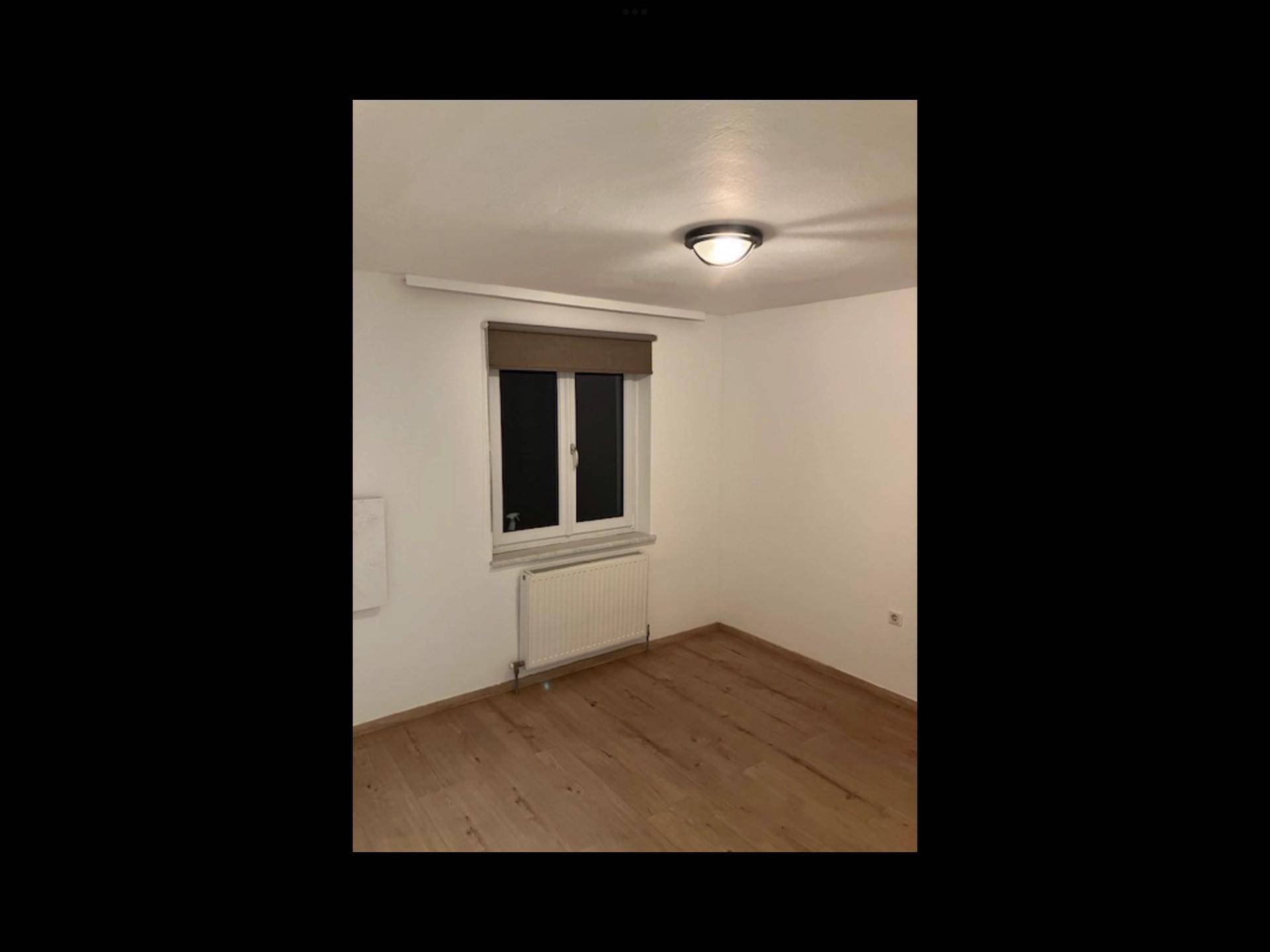 Helles Zimmer mit Holzboden und Zugang zu einem weiteren Raum, bereit zur Einrichtung.