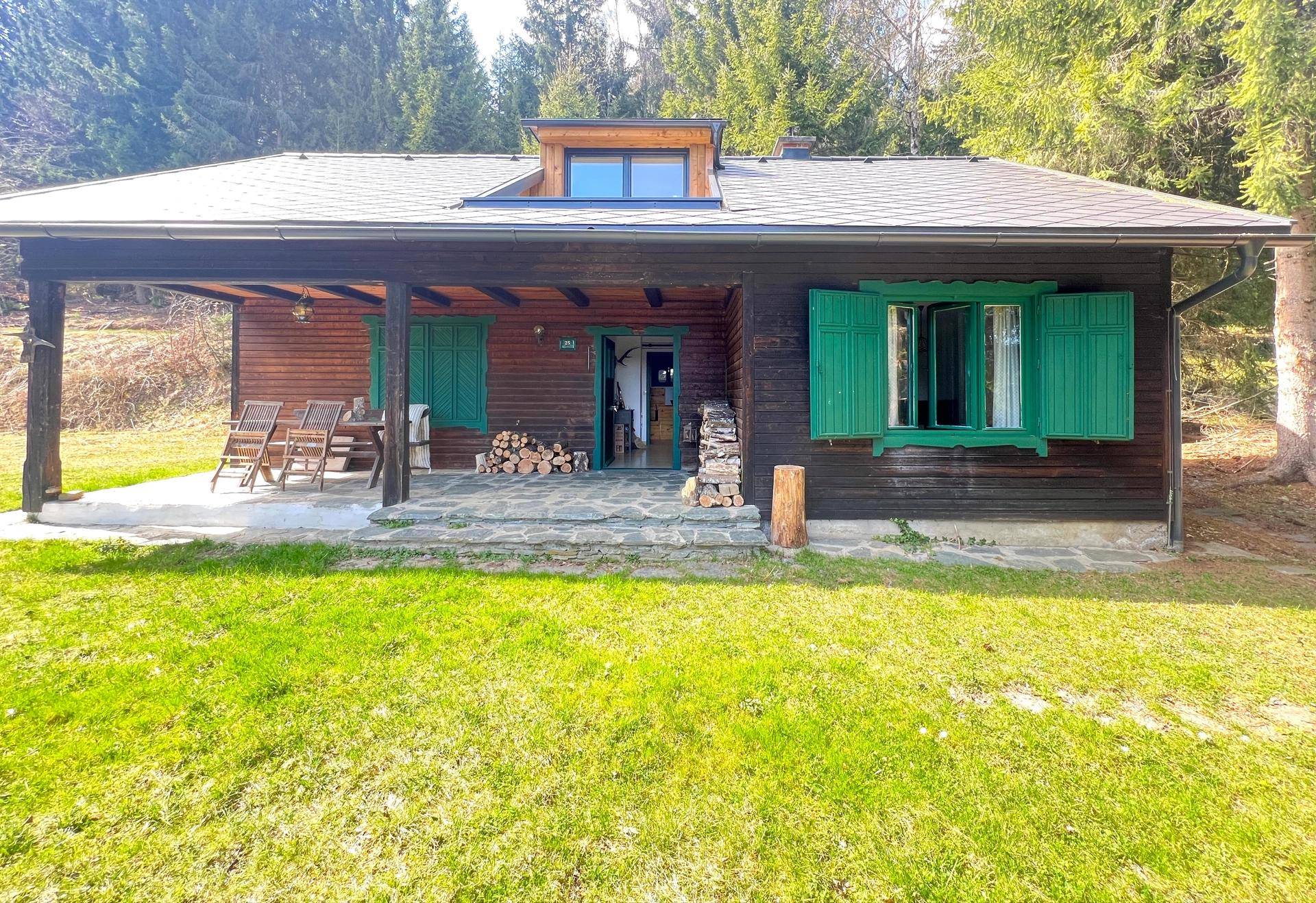 Gemütliche überdachte Terrasse vor dem Holzhaus mit Sitzgelegenheiten und Blick ins Grüne.