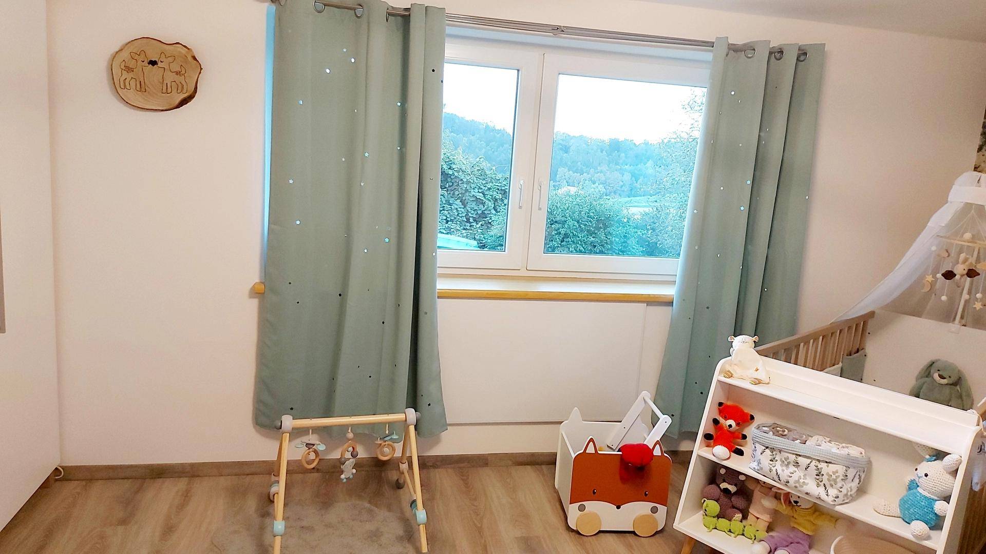 Helles Kinderzimmer mit Holzboden, Fenster und kindgerechter Dekoration.