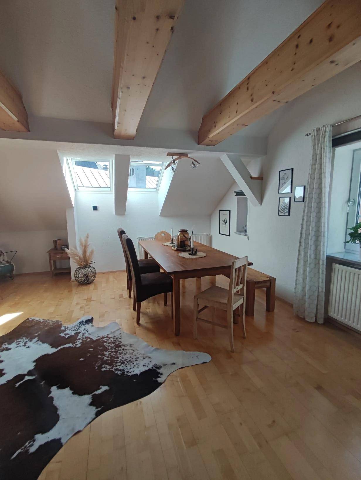Lichtdurchfluteter Wohn-Essbereich mit Holzbalken, Dachfenstern und Holzboden.