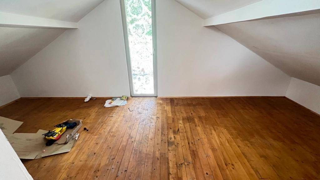 Geräumiger, leerer Dachbodenraum mit Holzboden und großem Fenster, bietet viel Potenzial.