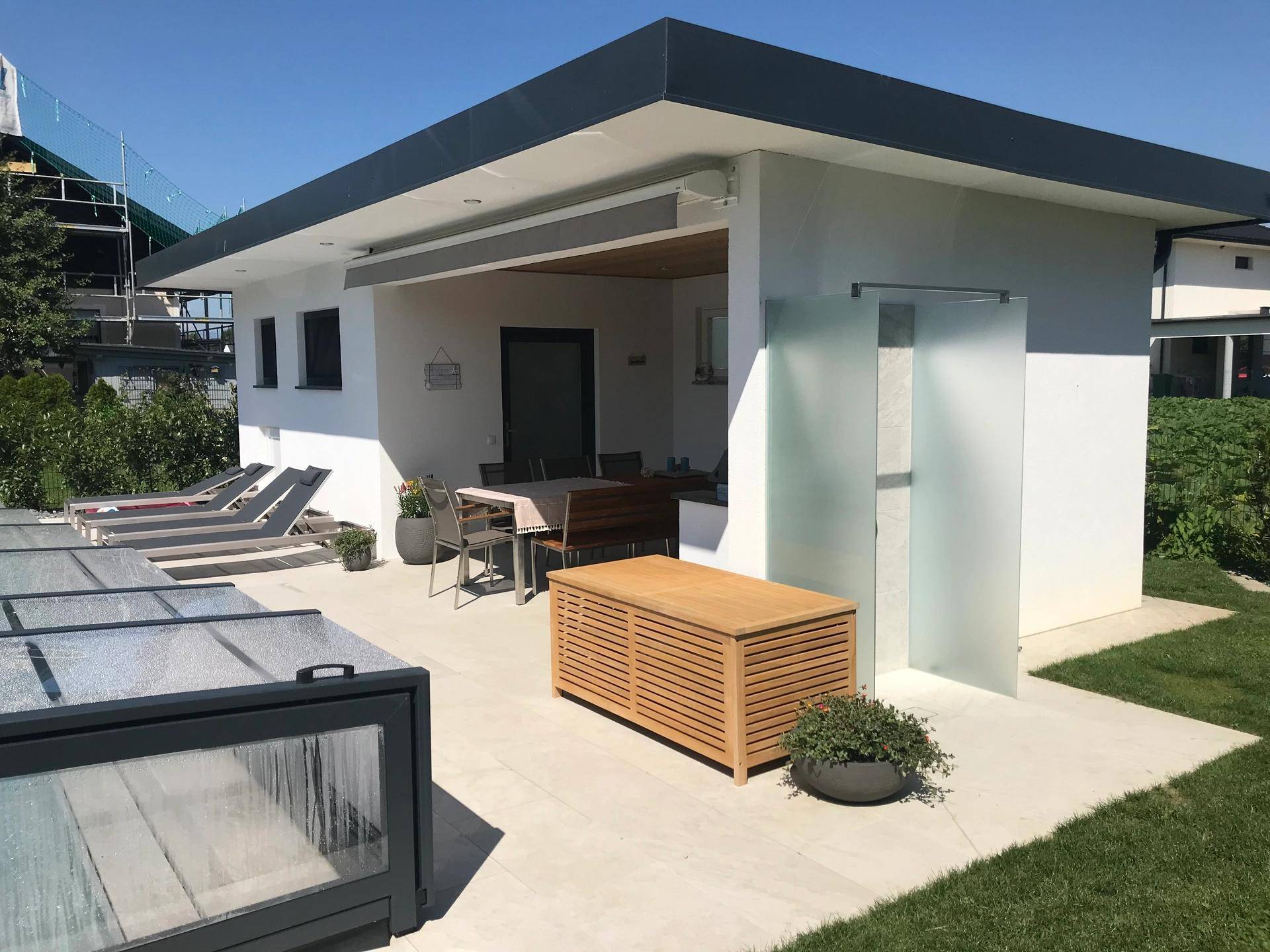 Gemütlicher Außenbereich am Poolhaus mit überdachter Terrasse und Essbereich.