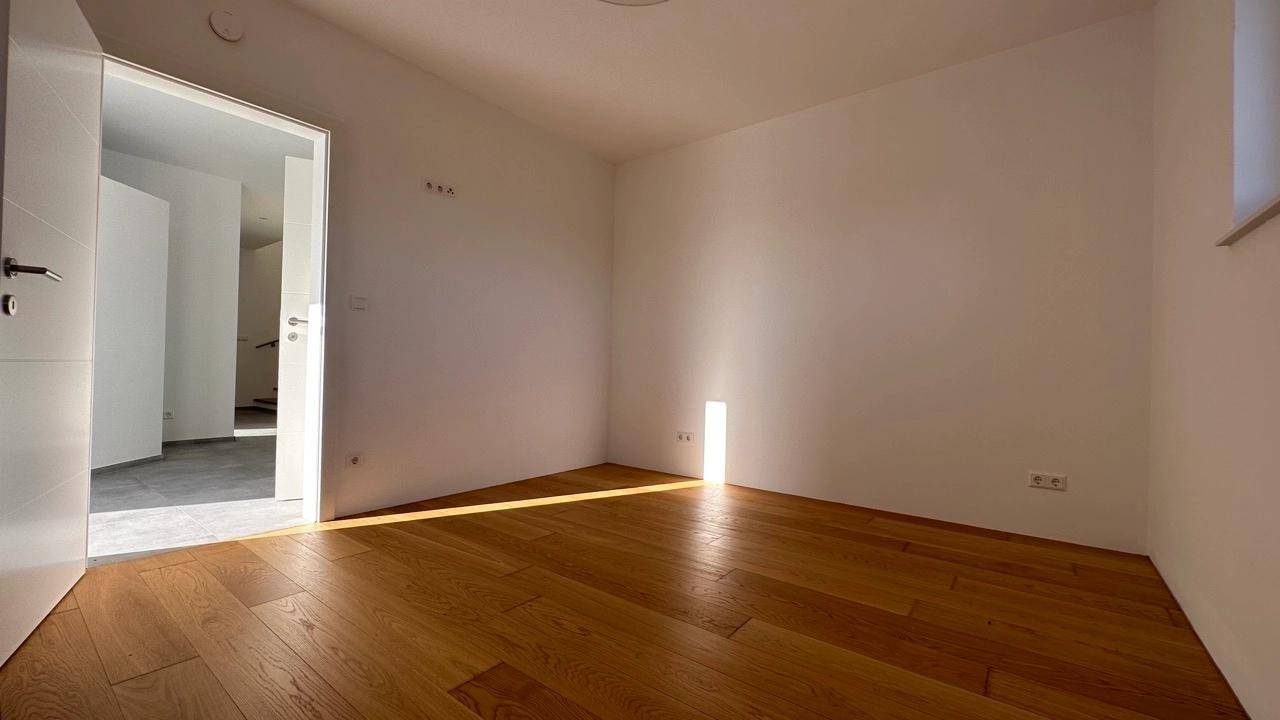 Heller, leerer Raum mit Holzboden und weiß gestrichenen Wänden, durchflutet von natürlichem Licht.