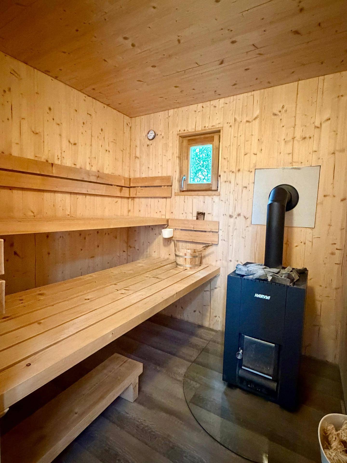 Helle Holzsauna mit traditionellem Ofen und bequemen Sitzbänken für Entspannung.