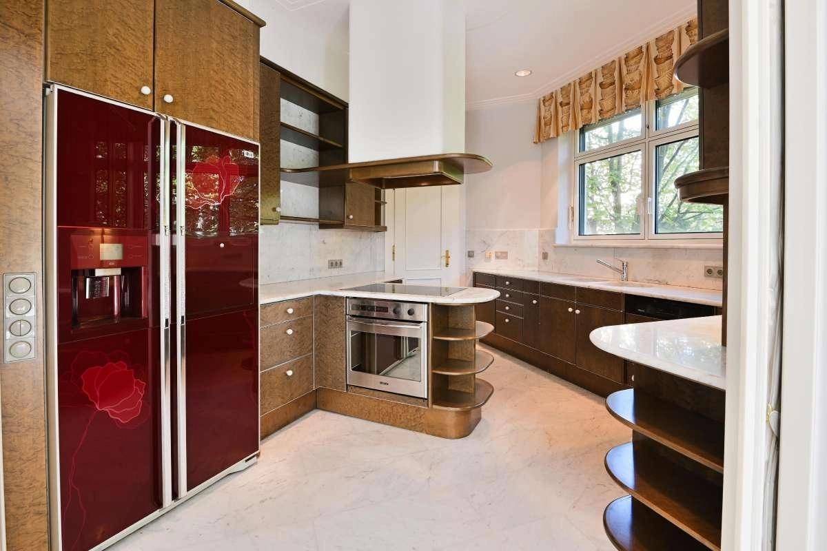 Einzigartige Küche mit dunklen Holzschränken, roten Design-Kühlschränken und Marmorarbeitsplatten.