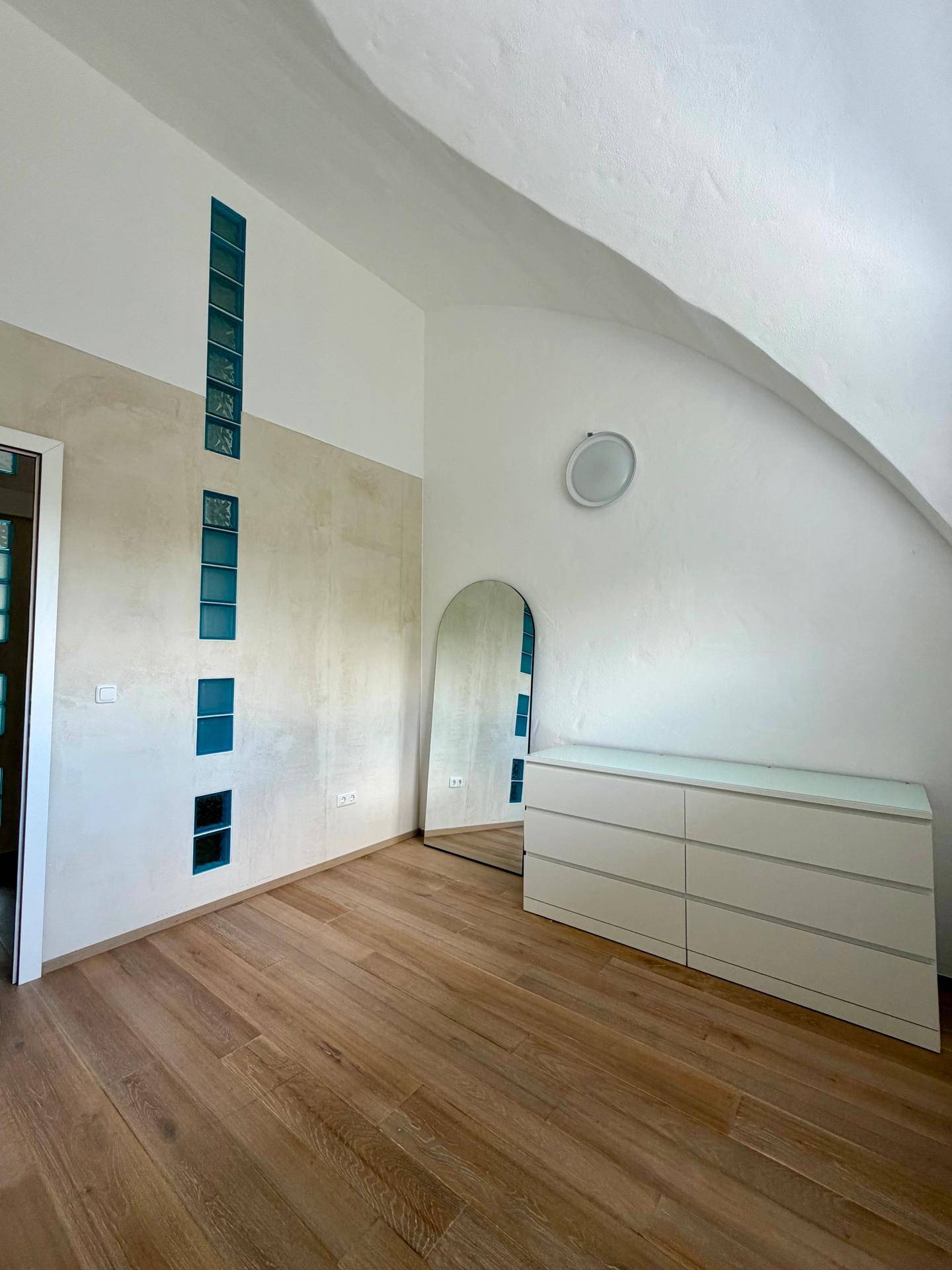 Geräumiges Schlafzimmer mit gewölbter Decke, Holzboden und integrierten weißen Kleiderschränken.