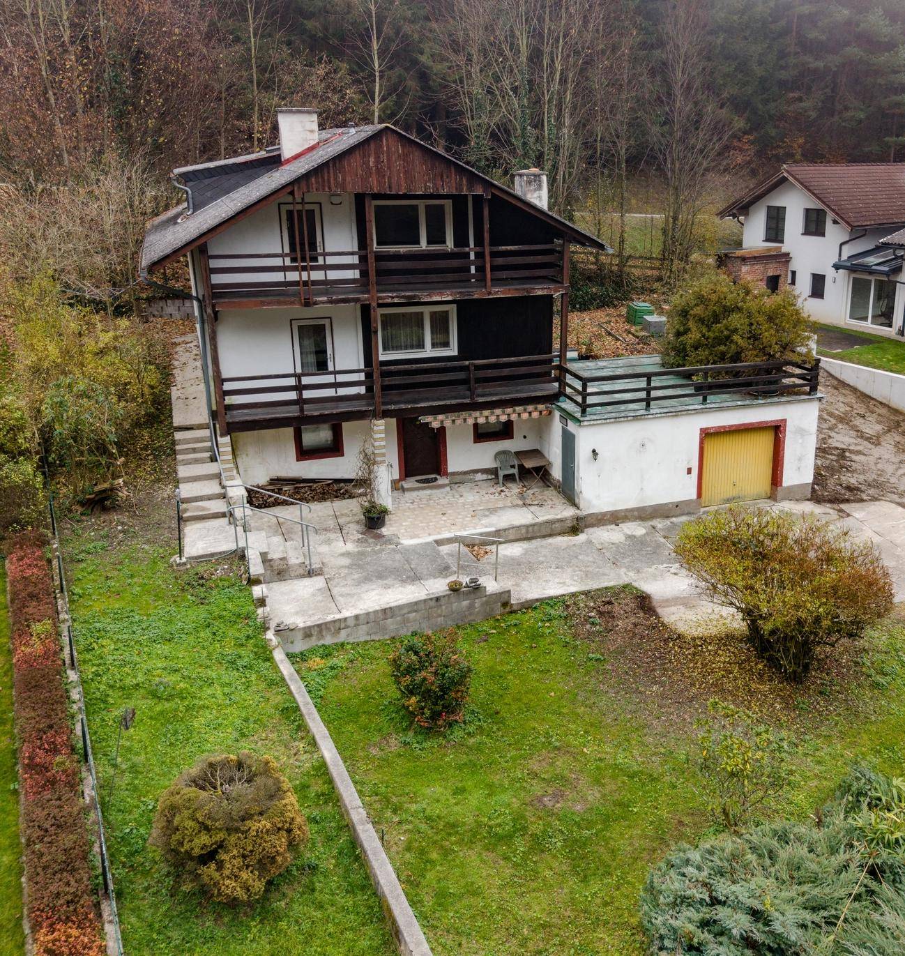 Gartenansicht des Hauses mit Rasenfläche, Sträuchern und Blick auf die umliegende Landschaft.
