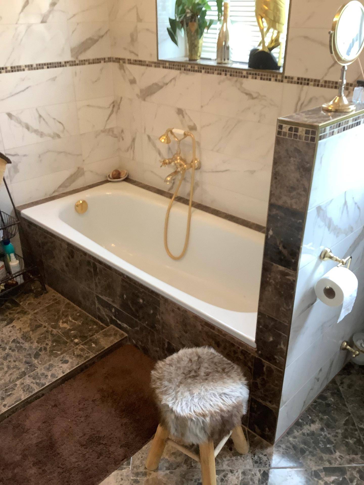 Badezimmer mit Badewanne und eleganten Marmorfliesen in Braun- und Weißtönen.