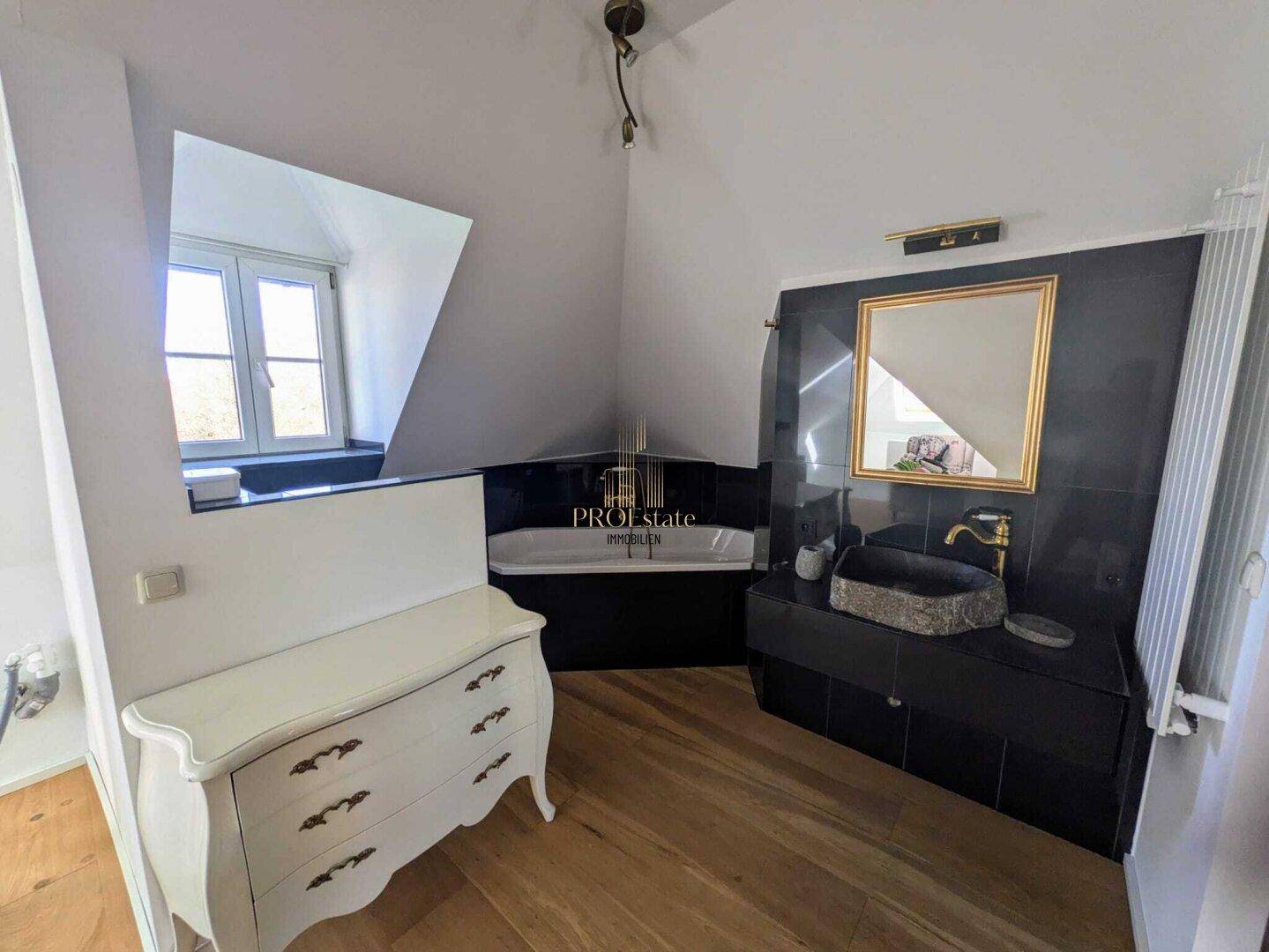Modernes Badezimmer mit dunklen Fliesen, Badewanne und stilvollem Steinwaschbecken.