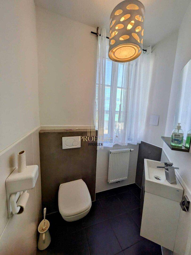 Kleines Gäste-WC mit wandhängender Toilette, modernem Waschbecken und Fenster.