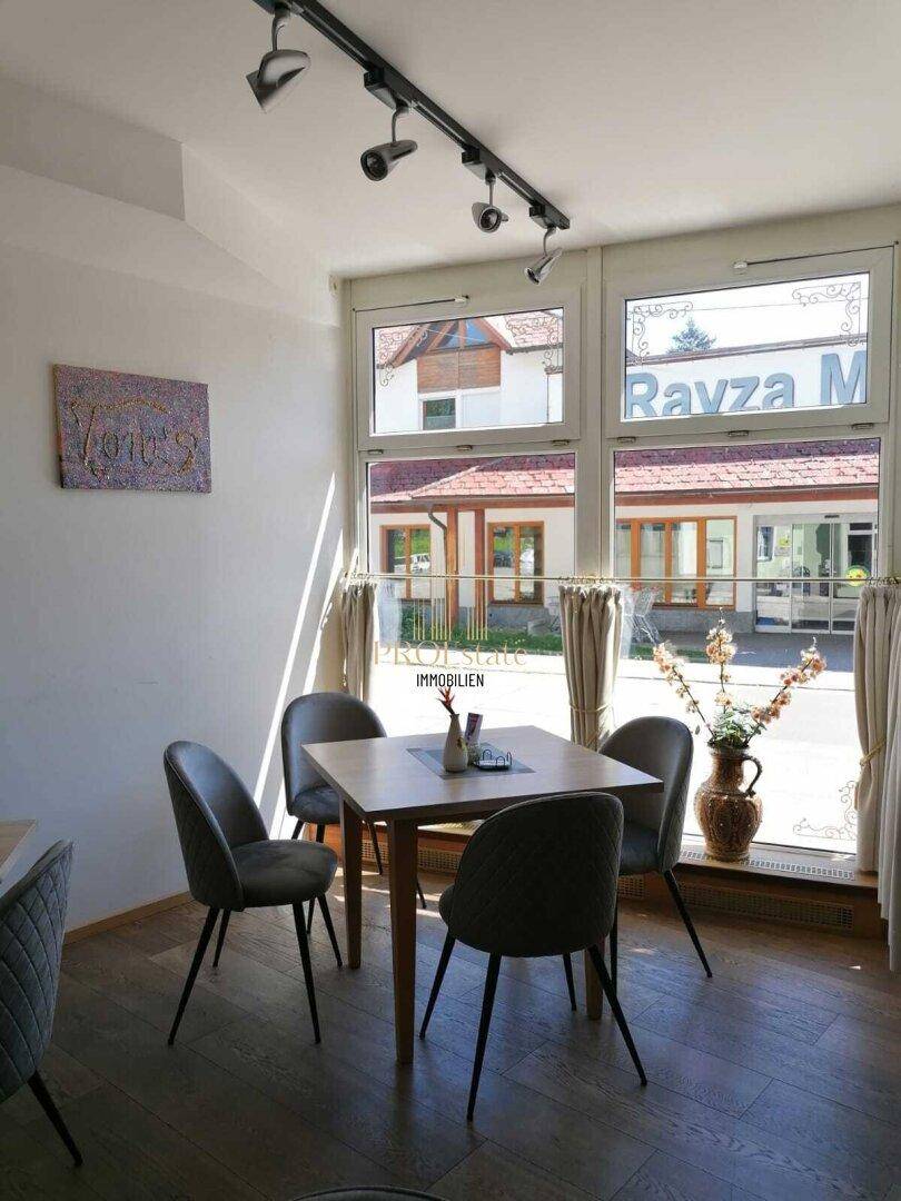 Heller Essbereich mit Holztisch, modernen Stühlen und großen Fenstern zur Straße.