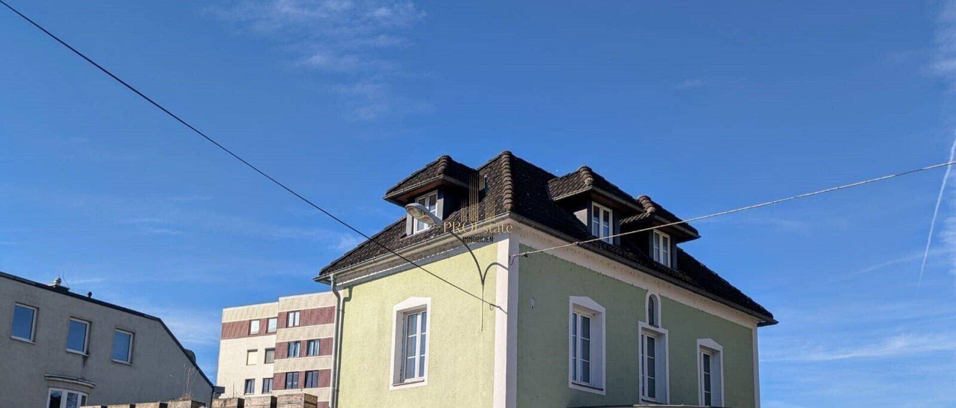 Oberer Teil eines historischen Gebäudes mit Mansarddach und Gaubenfenstern unter blauem Himmel.