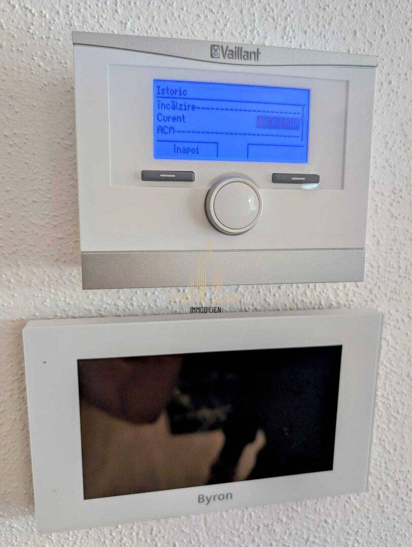 Nahaufnahme eines Vaillant Heizungsthermostats und einer Byron Gegensprechanlage an der Wand.