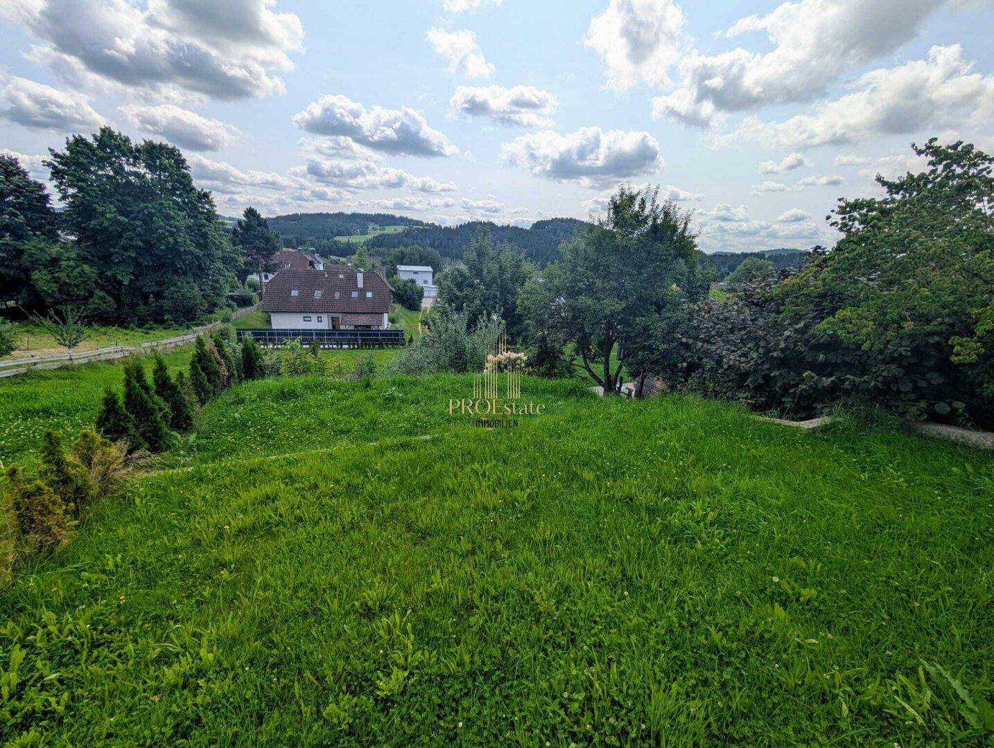 Großer, gepflegter Gartenbereich mit Rasenfläche und Blick auf die umliegende grüne Landschaft.