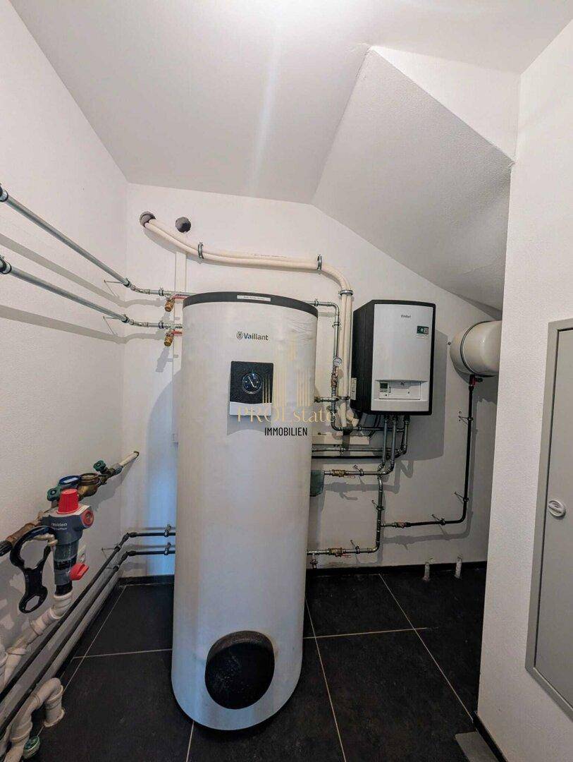 Technikraum mit Warmwasserspeicher und Heizungsanlage, sauber installiert und gut zugänglich.