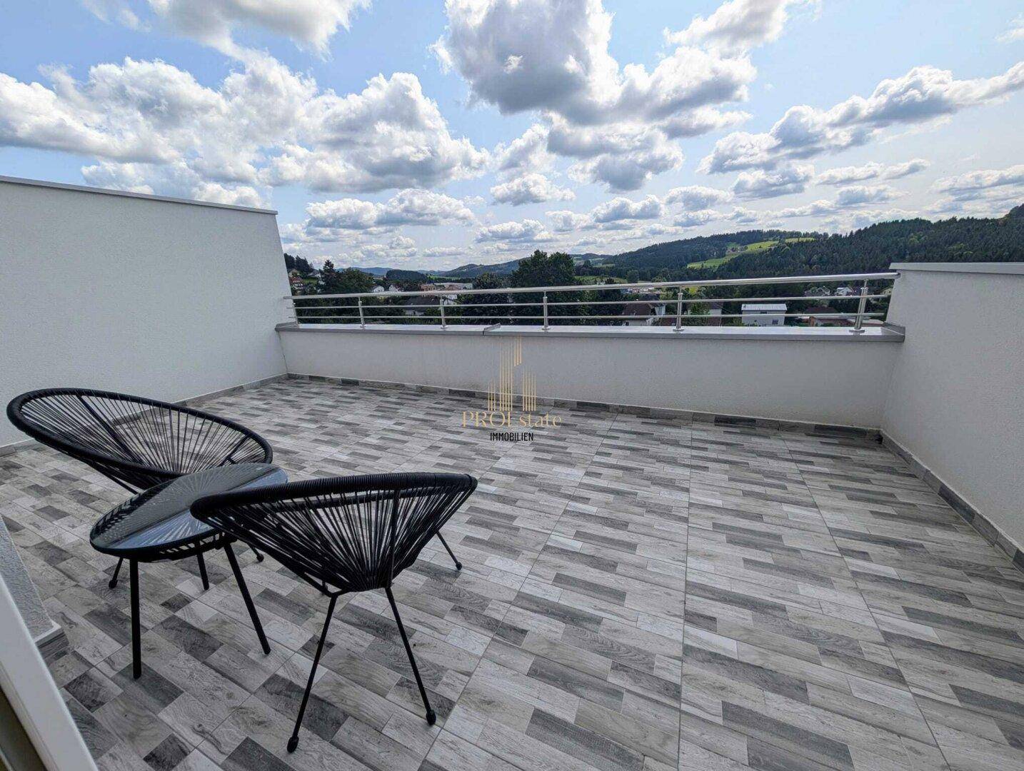 Geräumige Dachterrasse mit modernen Outdoor-Sesseln und Panoramablick über die Landschaft.