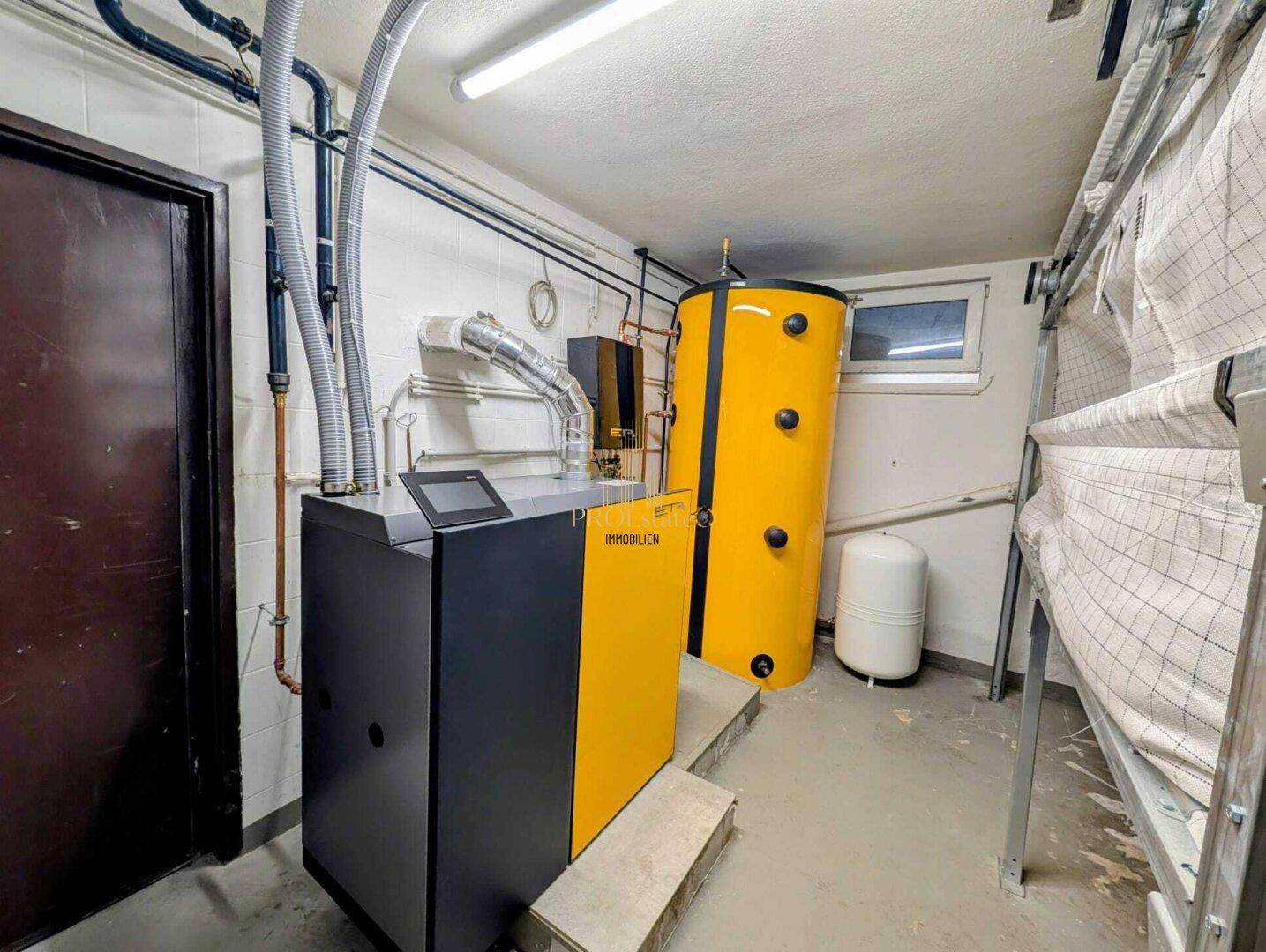 Heizungsraum im Keller mit moderner Pelletheizung und Warmwasserspeicher.