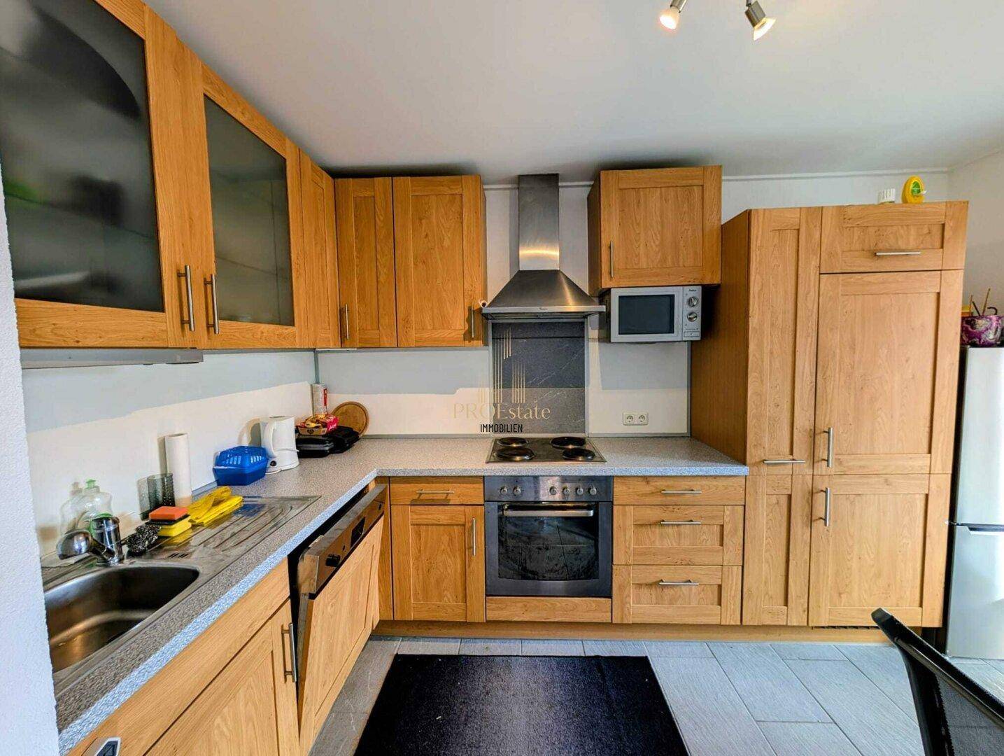 Funktionale Küche mit Holzschränken, integrierten Geräten und hellem Arbeitsbereich.