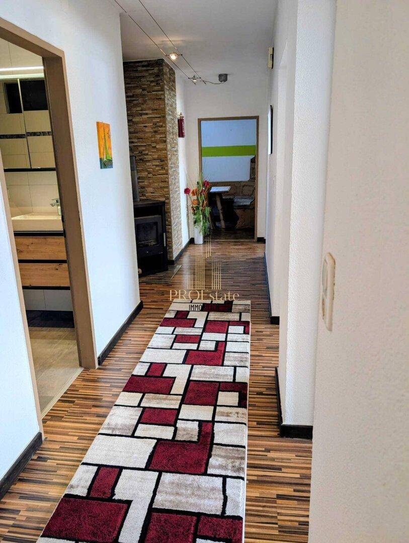 Heller Flur mit modernem Teppichläufer, Holzboden und Steinwandakzenten.