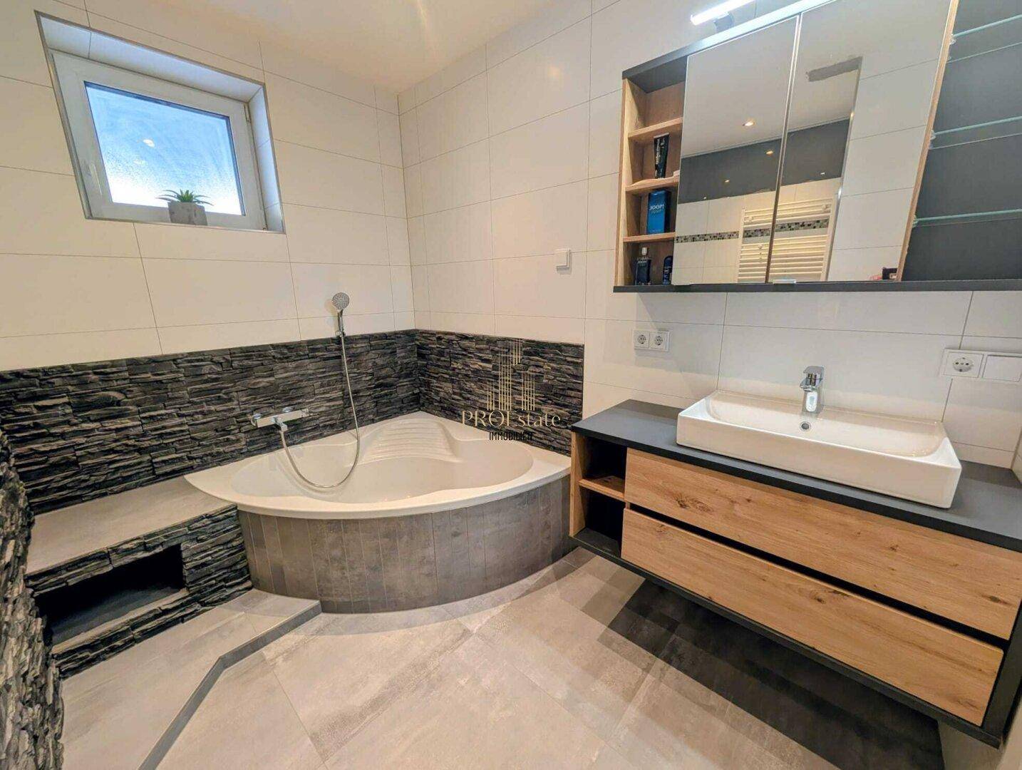 Geräumiges Badezimmer mit Eckbadewanne, modernem Waschtisch und Fenster für Tageslicht.