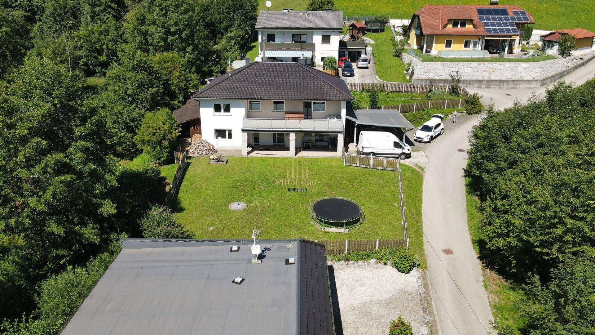 Übersicht des Einfamilienhauses mit großem Garten, Carport und ländlicher Umgebung.