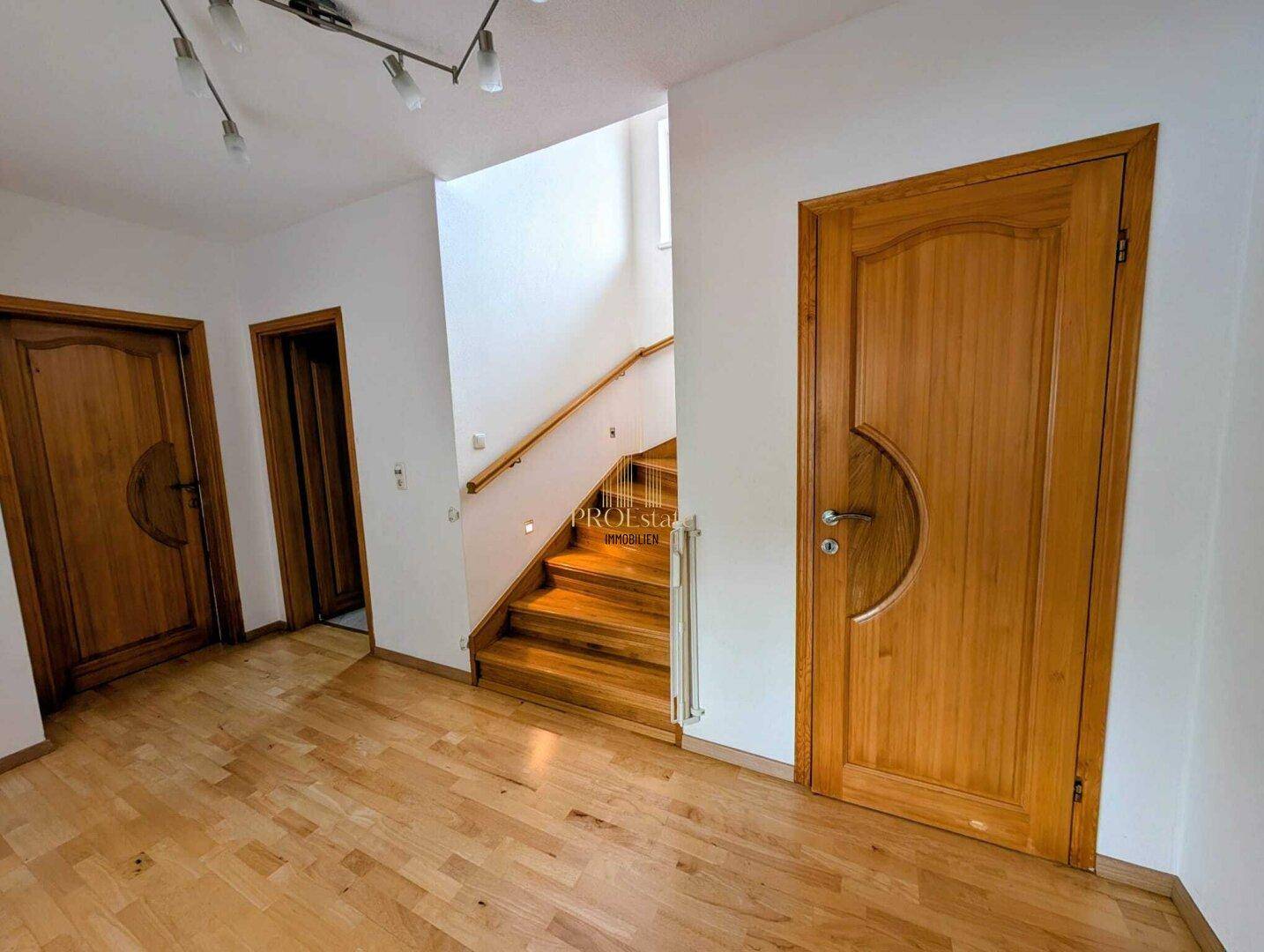 Geräumiger Flur mit Holzparkettboden und mehreren Holztüren, die zu den Zimmern führen.
