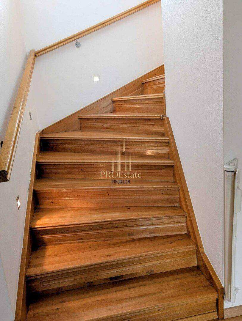 Holztreppe mit hellem Geländer, die die verschiedenen Etagen des Hauses verbindet.