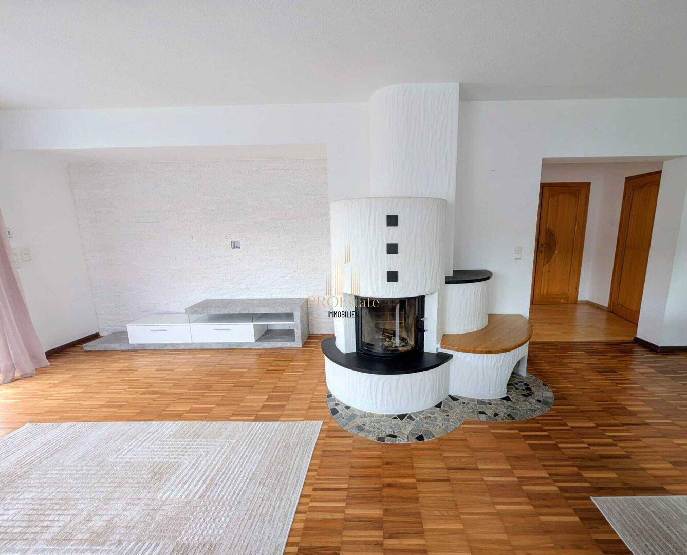 Geräumiges Wohnzimmer mit Parkettboden und einem modernen Kamin als zentralem Element.