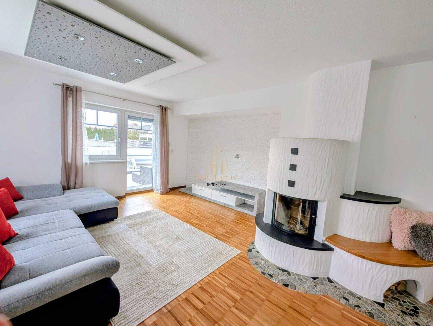 Helles Wohnzimmer mit Parkettboden, modernem Kamin und Zugang zur Terrasse.