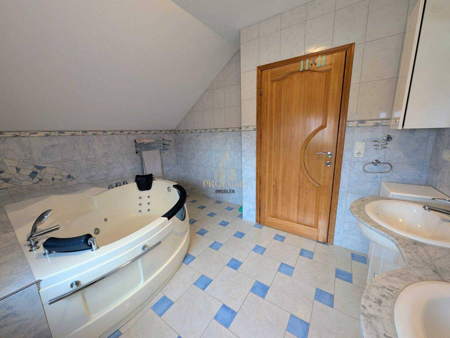 Geräumiges Badezimmer mit blauen Fliesen, Whirlpool-Badewanne und Dachschräge.
