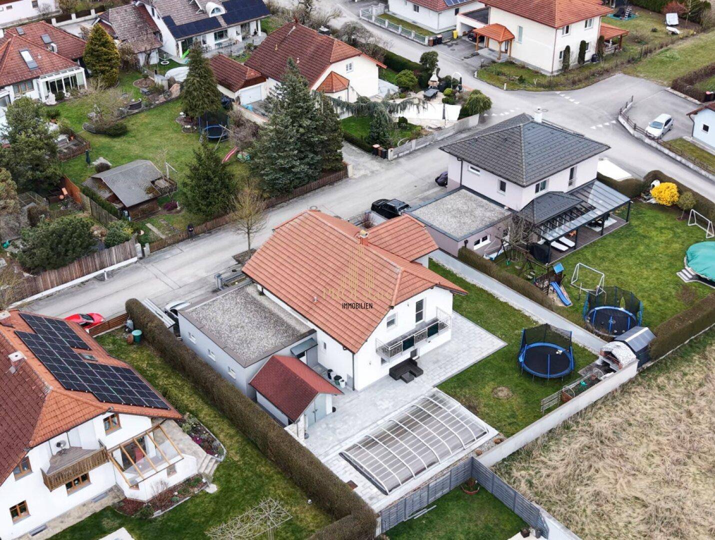 Luftaufnahme des Einfamilienhauses mit großem Garten, Pool und umliegender Nachbarschaft.