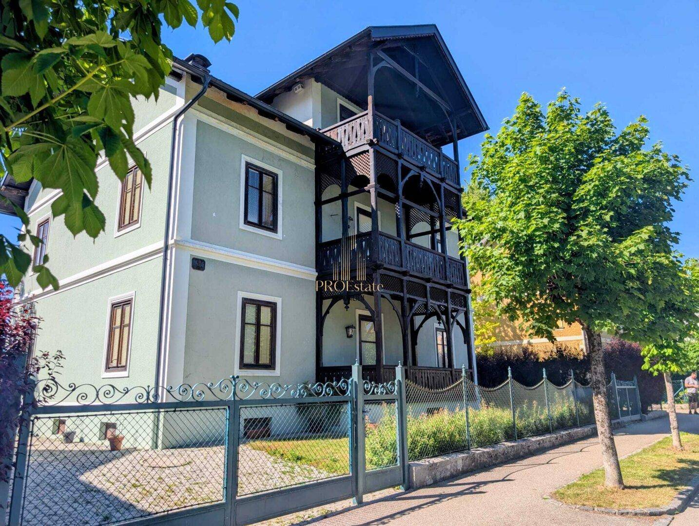 Seitenansicht des historischen Gebäudes von der Straße aus, mit markanten Holzveranden.